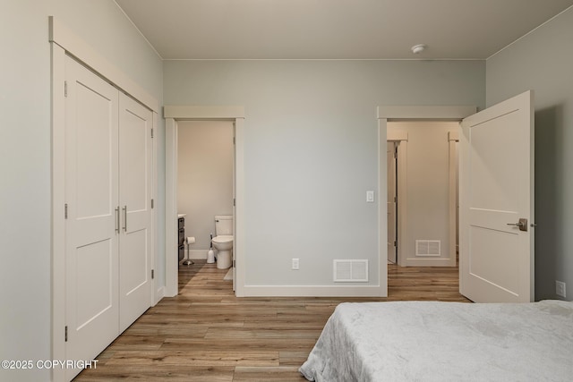 9475 E Spring Creek Cir, Wasilla, AK 99654 - bedroom featuring light wood-style flooring, connected bathroom, and baseboards