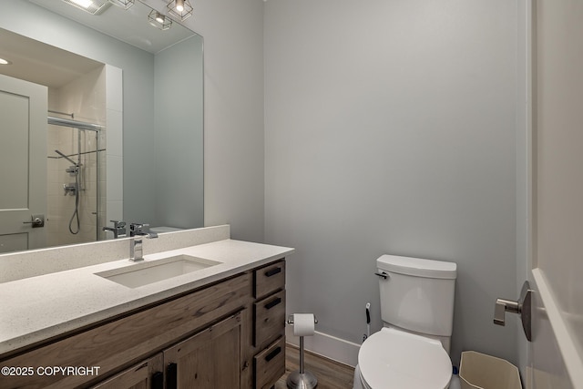 9475 E Spring Creek Cir, Wasilla, AK 99654 - bathroom featuring toilet, vanity, tiled shower, wood finished floors, and baseboards