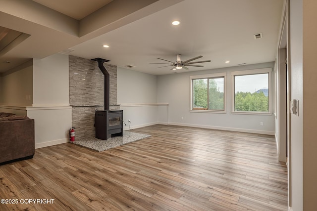 9475 E Spring Creek Cir, Wasilla, AK 99654 - unfurnished living room featuring a ceiling fan, a wood stove, light wood-style floors, recessed lighting, and baseboards