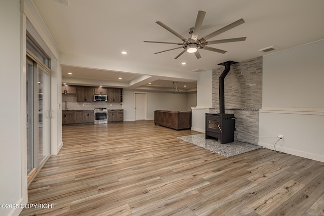 9475 E Spring Creek Cir, Wasilla, AK 99654 - unfurnished living room featuring ceiling fan, a wood stove, light wood finished floors, recessed lighting, and baseboards