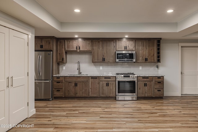 9475 E Spring Creek Cir, Wasilla, AK 99654 - kitchen with stainless steel appliances, a sink, light wood finished floors, decorative backsplash, and open shelves
