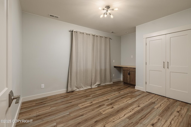 9475 E Spring Creek Cir, Wasilla, AK 99654 - unfurnished bedroom with light wood-style flooring, a closet, a chandelier, and baseboards