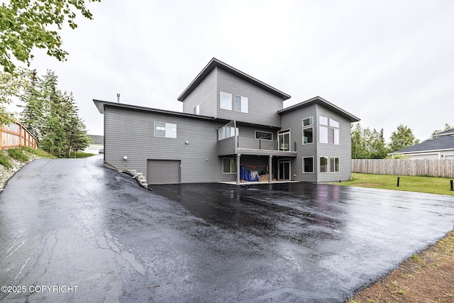 9475 E Spring Creek Cir, Wasilla, AK 99654 - back of house with asphalt driveway, an attached garage, and a balcony