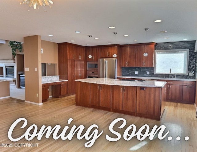 kitchen with a sink, decorative backsplash, a large island, appliances with stainless steel finishes, and light wood-type flooring