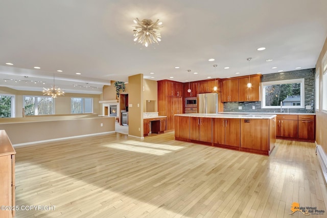 kitchen with light wood-type flooring, stainless steel appliances, an inviting chandelier, light countertops, and decorative backsplash