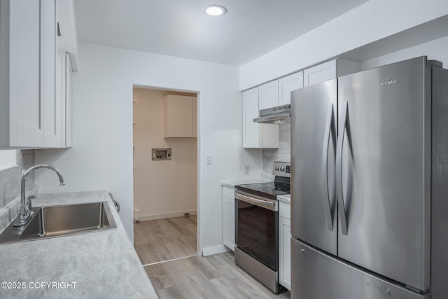 kitchen with under cabinet range hood, stainless steel appliances, light countertops, and a sink