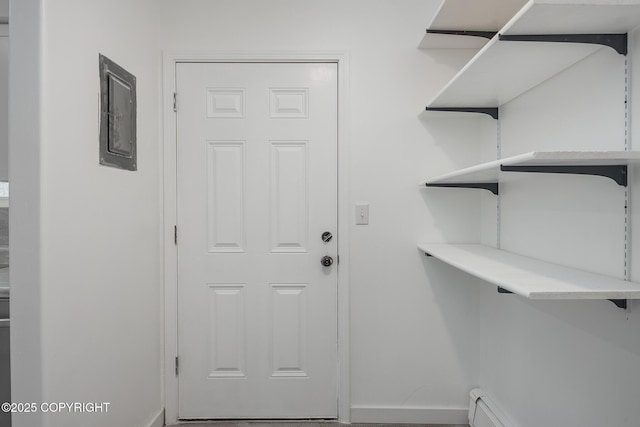 clothes washing area featuring a baseboard heating unit and baseboards