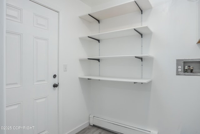 laundry room featuring wood finished floors, baseboards, laundry area, washer hookup, and baseboard heating