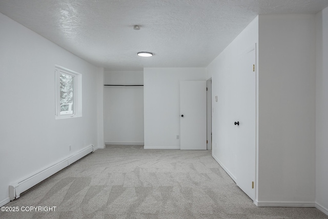 unfurnished bedroom with a baseboard heating unit, baseboards, a textured ceiling, and carpet flooring