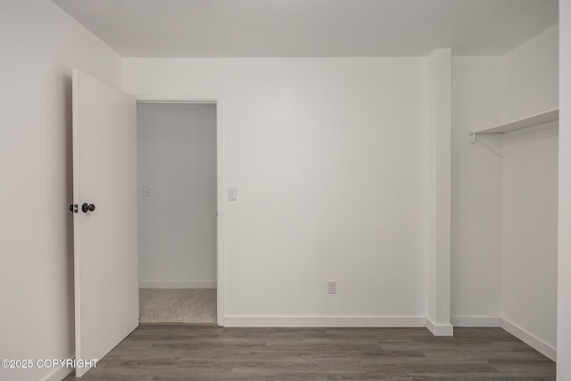 spare room featuring baseboards and dark wood-style flooring