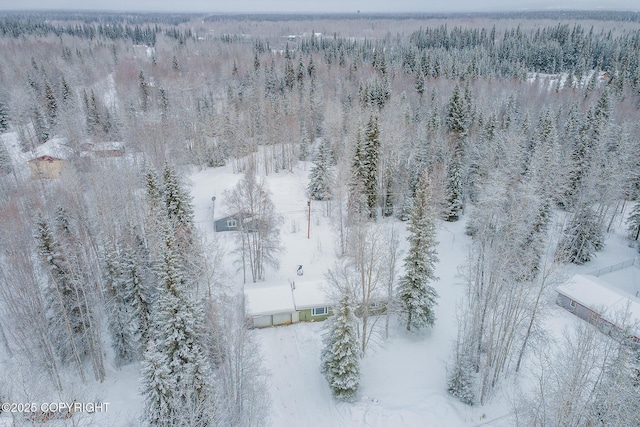 snowy aerial view featuring a wooded view