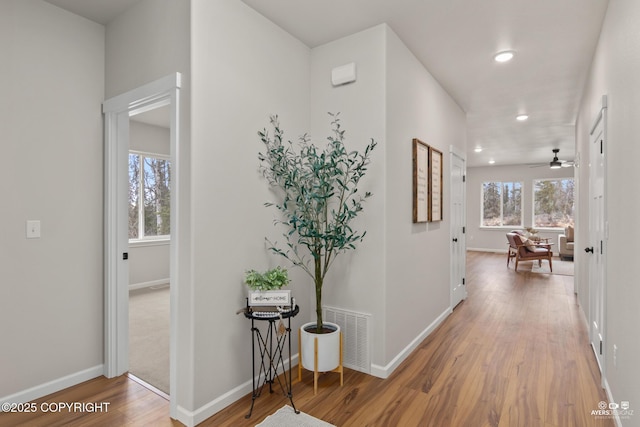 corridor with wood finished floors, visible vents, and baseboards