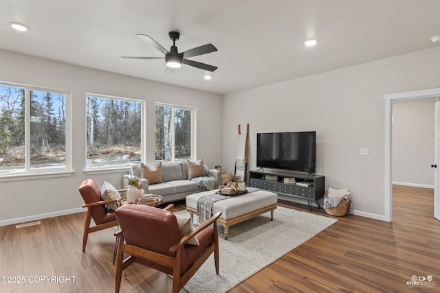 living area featuring baseboards, plenty of natural light, wood finished floors, and a ceiling fan