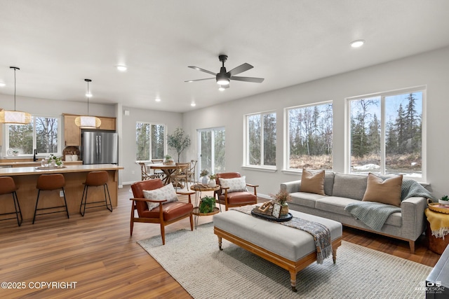 living area with recessed lighting, baseboards, a ceiling fan, and wood finished floors