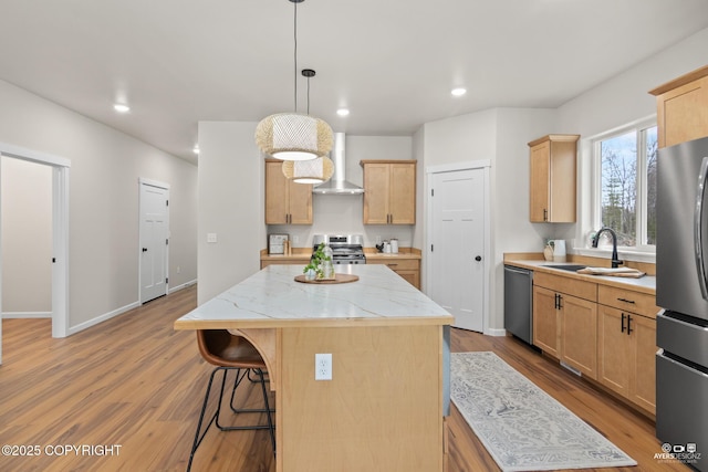 kitchen featuring light brown cabinetry, a sink, a kitchen island, stainless steel appliances, and wall chimney exhaust hood