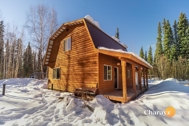 view of snow covered exterior with a gambrel roof and metal roof