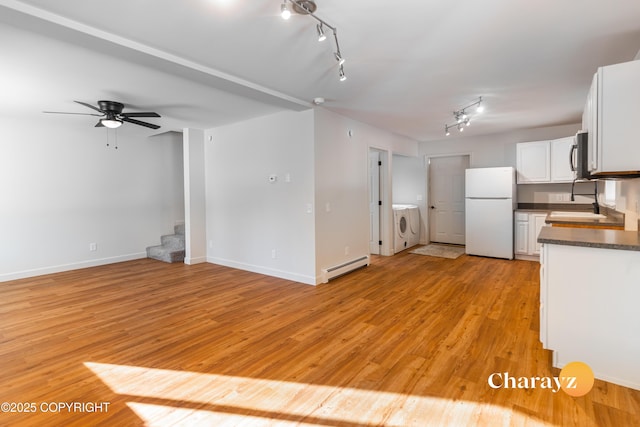 kitchen featuring a baseboard heating unit, stainless steel microwave, dark countertops, freestanding refrigerator, and white cabinets