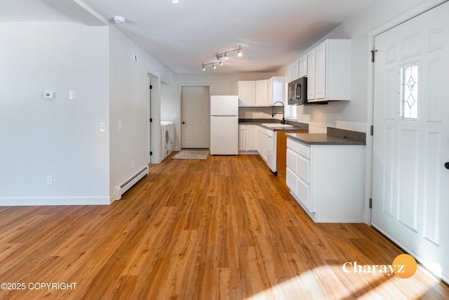 kitchen featuring freestanding refrigerator, a sink, washer and dryer, dark countertops, and baseboard heating