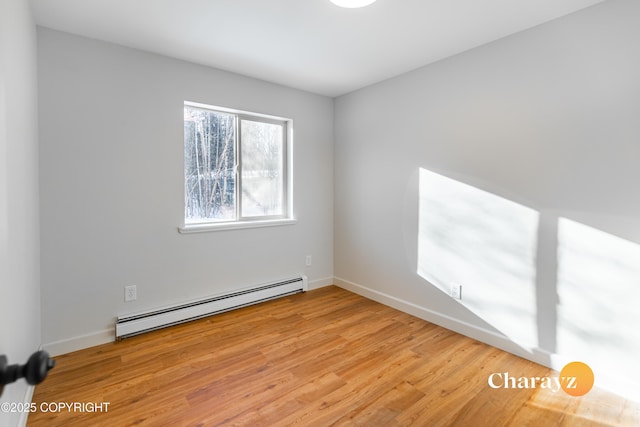 empty room featuring wood finished floors, baseboards, and a baseboard radiator