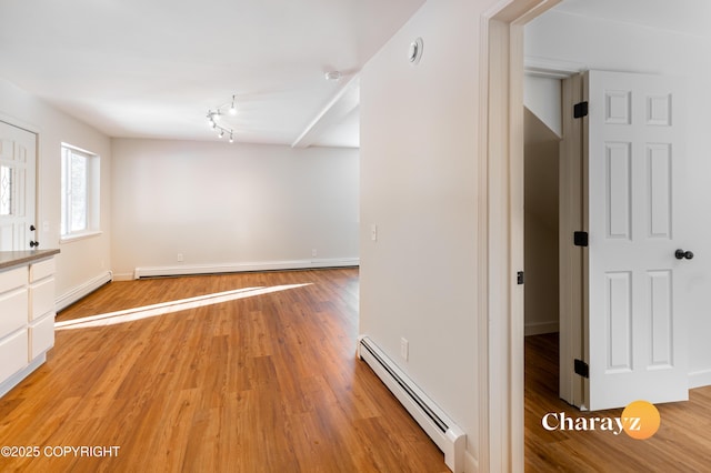 interior space featuring light wood-style flooring, a baseboard heating unit, baseboards, and a baseboard radiator