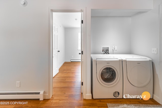 clothes washing area with a baseboard radiator, laundry area, light wood-style floors, washing machine and dryer, and baseboard heating