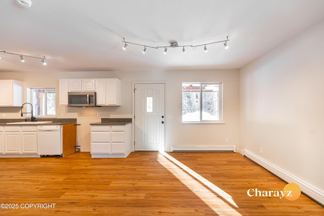 kitchen featuring a sink, stainless steel microwave, white dishwasher, and a baseboard radiator