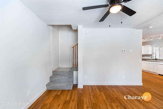 interior space with light wood-type flooring, stairs, baseboards, and a sink