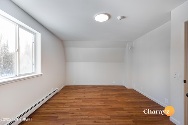 bonus room featuring a baseboard heating unit, baseboards, wood finished floors, and vaulted ceiling