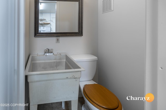 half bathroom featuring visible vents, toilet, and vanity