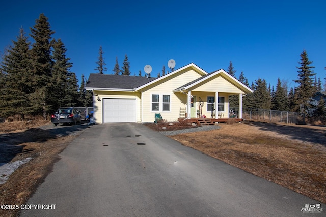 view of front of house with aphalt driveway, a porch, fence, and a garage