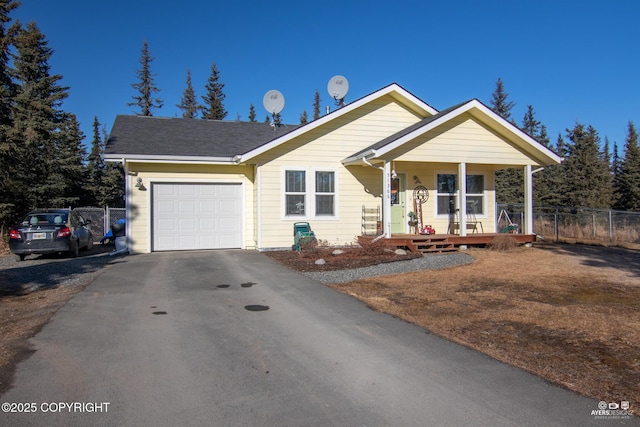 view of front of home featuring aphalt driveway, an attached garage, fence, and covered porch