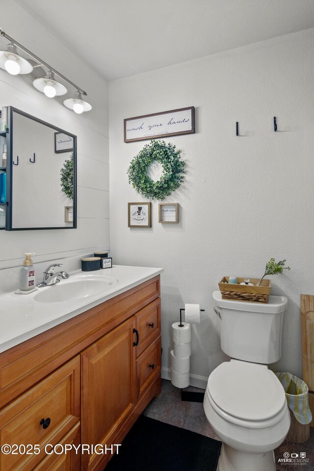 bathroom featuring toilet, vanity, and baseboards