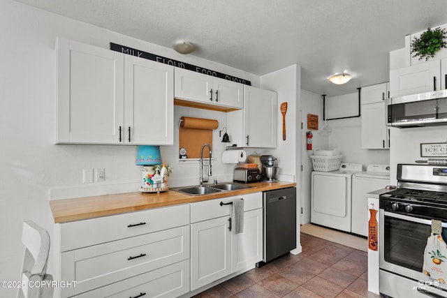 kitchen featuring wooden counters, a sink, appliances with stainless steel finishes, white cabinetry, and washer and clothes dryer