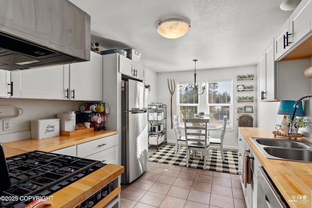 kitchen featuring light tile patterned flooring, stainless steel appliances, hanging light fixtures, wood counters, and a chandelier