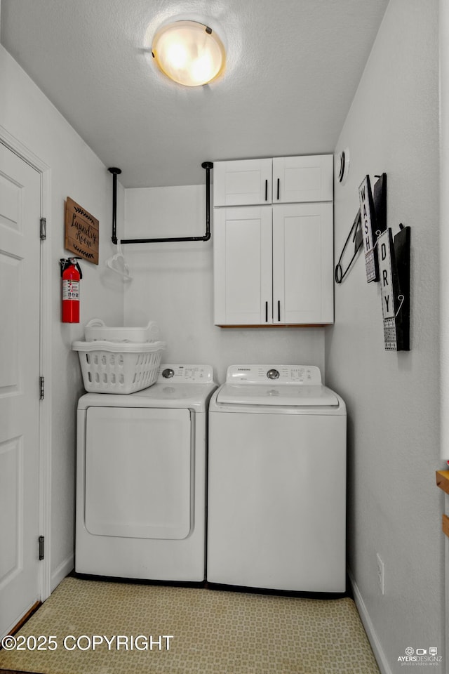 laundry area featuring washer and dryer, baseboards, cabinet space, and a textured ceiling