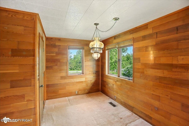 24508 Reese Rd, Chugiak, AK 99567 - unfurnished dining area with a chandelier, wooden walls, and light carpet