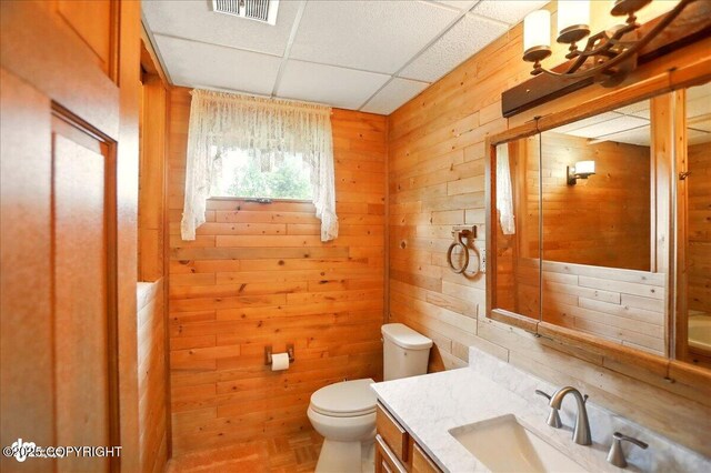 24508 Reese Rd, Chugiak, AK 99567 - bathroom with wood walls, toilet, a paneled ceiling, and vanity