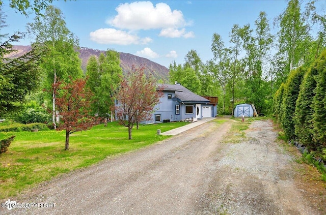 24508 Reese Rd, Chugiak, AK 99567 - tri-level home with driveway, an attached garage, a front lawn, and a mountain view