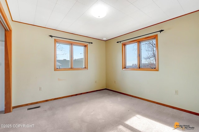 spare room with visible vents, baseboards, ornamental molding, and carpet flooring