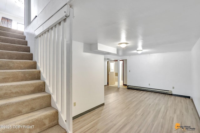 below grade area featuring a baseboard radiator, baseboards, light wood-style flooring, and stairs