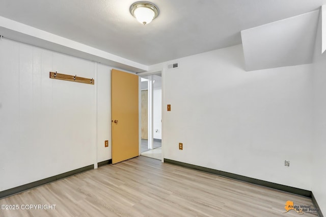 empty room with light wood-type flooring, visible vents, and baseboards