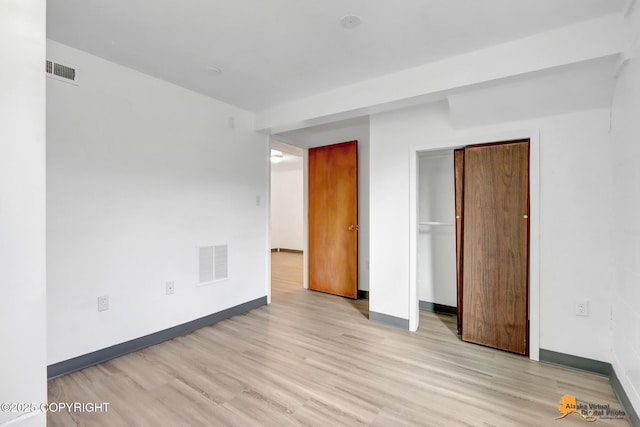 unfurnished bedroom with light wood-style floors, visible vents, a closet, and baseboards