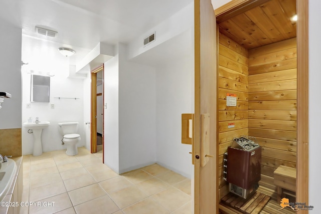 bathroom with tile patterned floors, visible vents, toilet, and a bathing tub