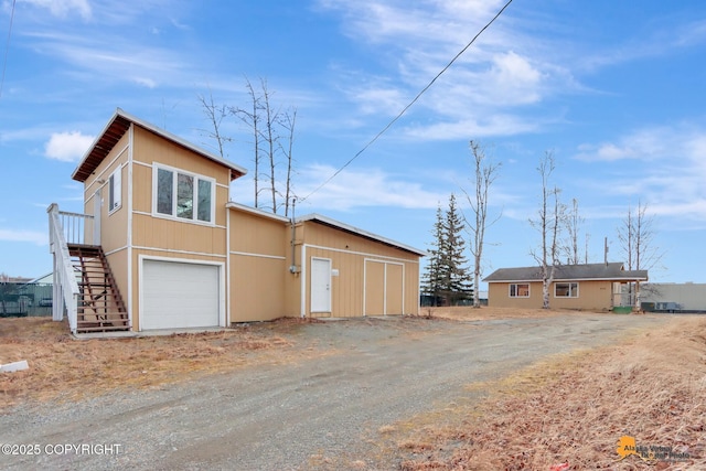 exterior space featuring stairway, an attached garage, and driveway