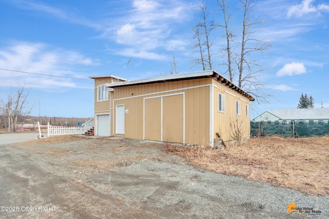 view of outdoor structure featuring an outdoor structure, fence, and driveway