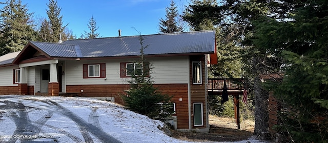 snow covered property featuring metal roof and a deck