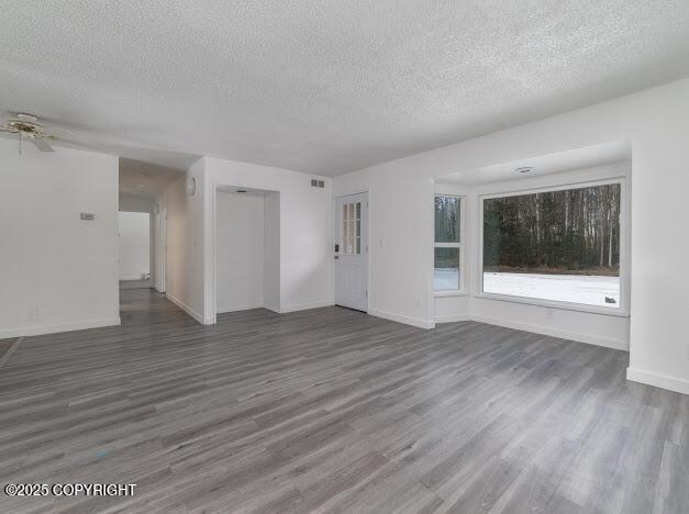 unfurnished living room with wood finished floors, visible vents, and baseboards