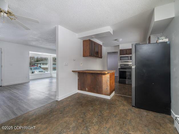 kitchen with a textured ceiling, open floor plan, appliances with stainless steel finishes, a peninsula, and baseboard heating