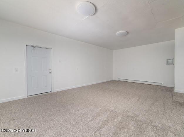 unfurnished room featuring a baseboard radiator, carpet floors, and baseboards