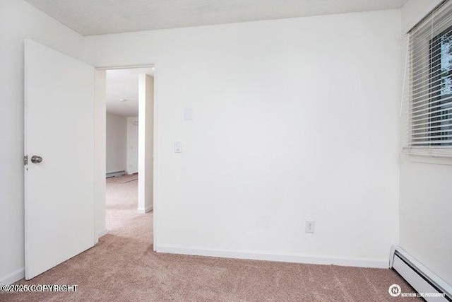 empty room featuring a baseboard radiator, baseboards, light colored carpet, and a baseboard heating unit